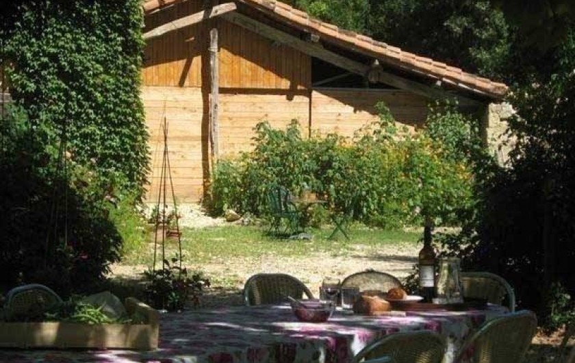 Location de vacances - Maison - Villa à Castéra-Verduzan - la table des repas sous les arbres, au fond la grange avec la cuisine d'été