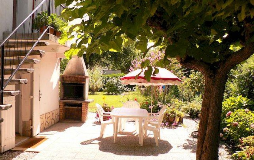 Terrasse avec table, fauteuils de jardin, parasols et barbecue