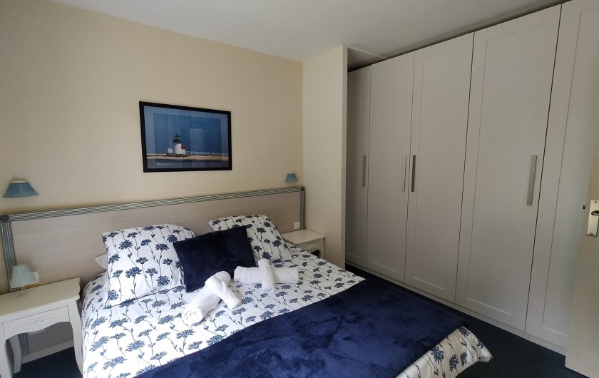 Location de vacances - Appartement à Cabourg - Vue de la chambre. Mur du fond équipé de rangements et penderie