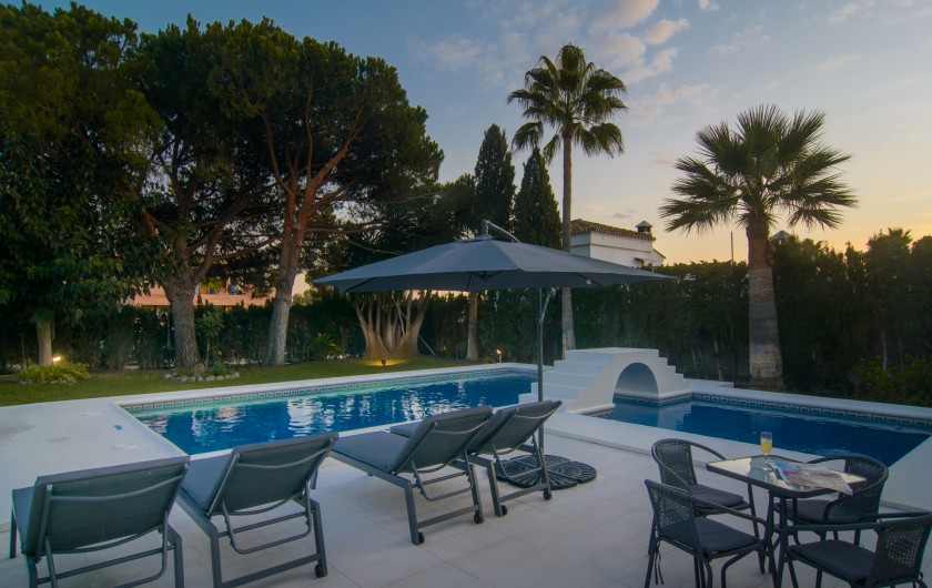 Location de vacances - Chalet à Marbella - Patio soigné avec carreaux de marbre, chaises longues et parasol.