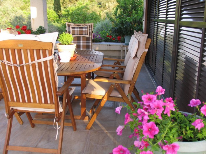 Location de vacances - Villa à Corfu - Veranda with wooden furniture and flower bed.