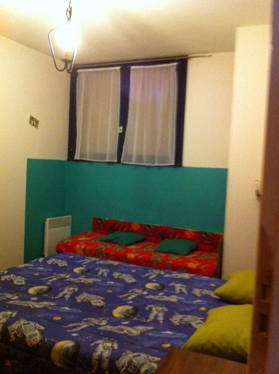 Location de vacances - Appartement à Super Besse - vue en entrant dans la chambre : lit double (bleu)+ lit d'enfant (rouge)