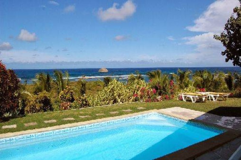 Location de vacances - Villa à Saint-François - Façade principale et terrasse vue sur mer. Meubles extérieurs et piscine.